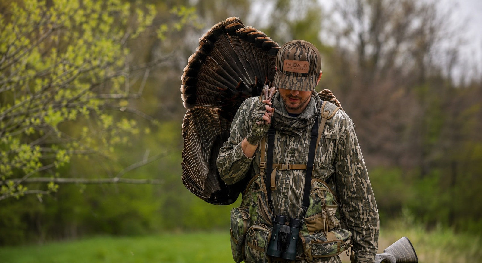 Zak carrying a wild turkey while wearing a TRUEWILD Featherworks Bottomland hat
