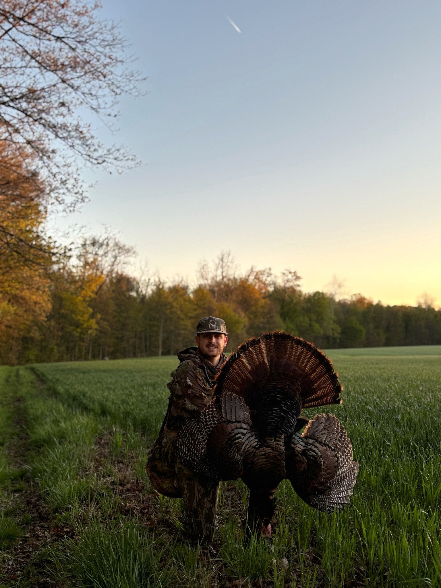 Zak with a wild turkey in a field at sunset